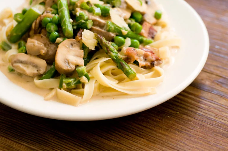 Pasta primavera with asparagus, peas, mushrooms, and bacon